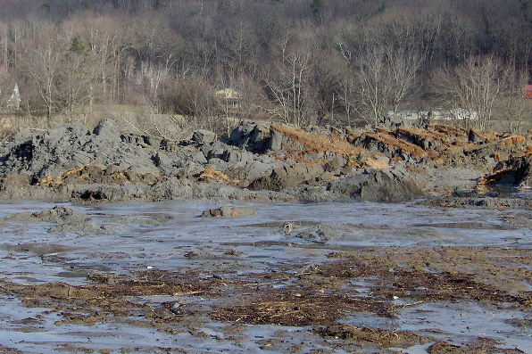 A coal ash pond surrounded by rocks and barren trees.