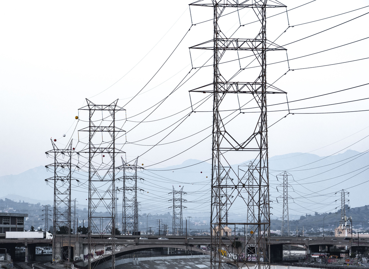 A view of electricity towers against mountainous landscape in an urban area.