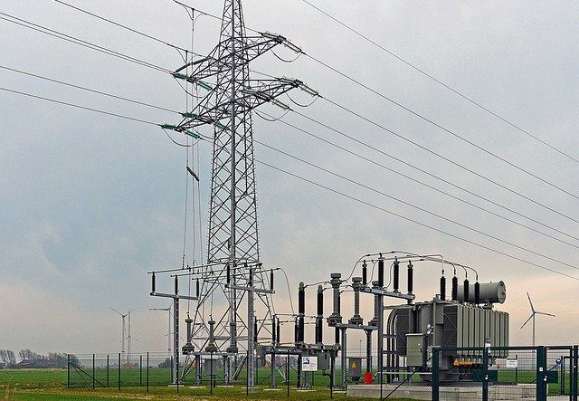 High voltage power lines and transformer set against a gray sky.