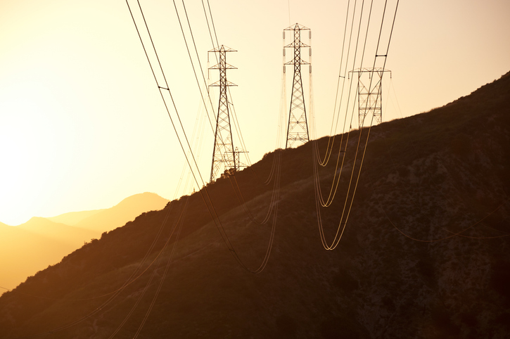 Power lines on top of a mountain at sunset.