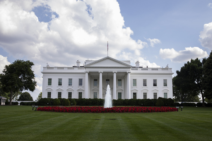 The White House in Washington, D.C. White fluffy clouds above it, water fountain in front of the building.